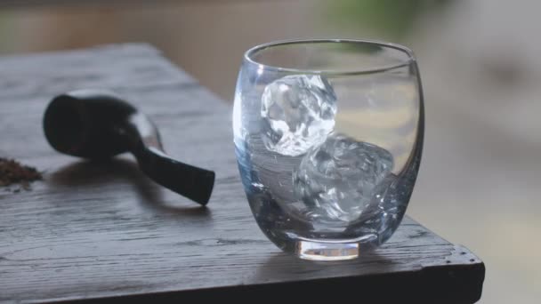 冰块缓缓地落在一个冒烟的老式桌子上的杯子里 威士忌立即从瓶子里倒进杯子里 — 图库视频影像