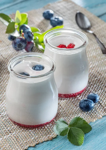 Two glass containers with plain yoghurt and berries on the table. Light summer mood.