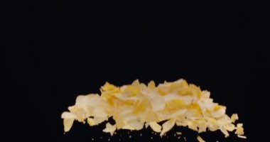 Doğal patates cipsi siyah arka planda yükselip alçalır. Yavaş Hareket 300 fps Blackmagic Ursa Pro G2.