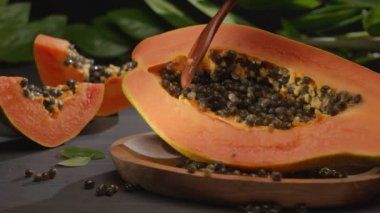 Tahta kaşıkla bir el tohumlardan papaya meyvesini temizler. Kameranın soldan sağa yatay yavaş hareketi. 