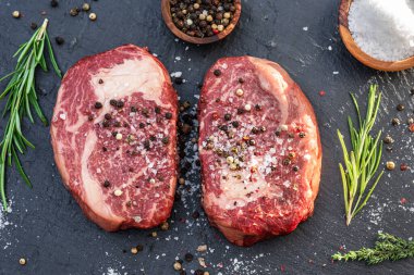 Gri tahtada tuzlu ve otlu çiğ pirzola bifteği. Üst görünüm.
