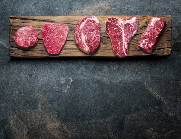 Différents Steaks Boeuf Crus Sur Planche Bois Sur Table Grise — Photo