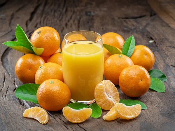 Orangefarbene Mandarinenfrüchte Und Ein Glas Frischer Mandarinensaft Auf Dunklem Holzgrund — Stockfoto