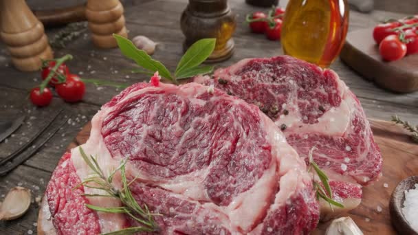 Twee Rauwe Rib Oogsteaks Met Specerijen Kruiden Een Houten Keukentafel — Stockvideo