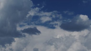 Yakın plan 4K hızlandırılmış mavi güneşli gökyüzünde beyaz büyük bulutların videosu. Yaz mavi bulutlu gökyüzü zaman atlaması. Bulutların arasında bir uçak uçurmanın etkisi.