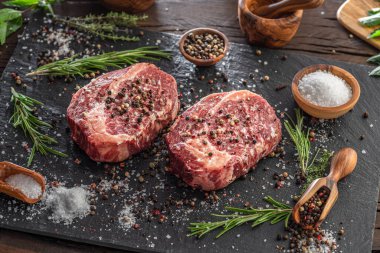 Gri tahtada tuzlu ve otlu çiğ pirzola bifteği. Üst görünüm.