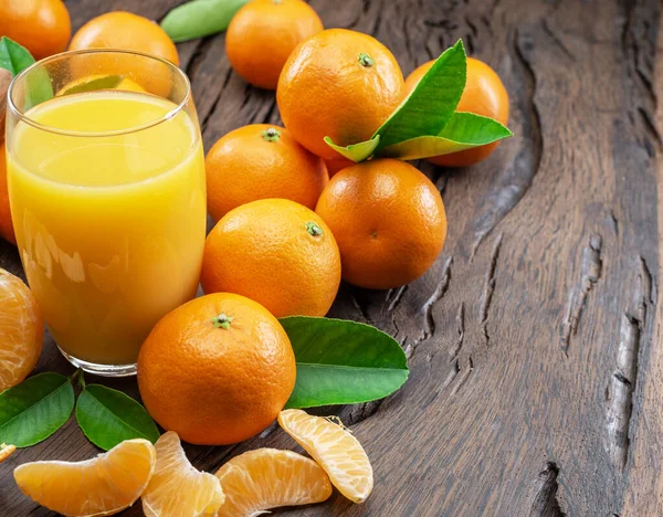 Orangene Mandarinenfrüchte Und Ein Glas Frischer Mandarinensaft Auf Dunklem Holzgrund — Stockfoto