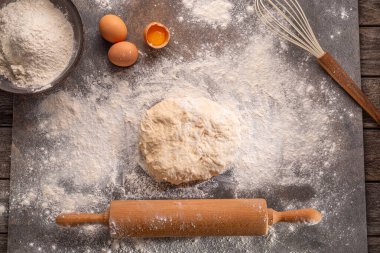Pişmiş hamura hazır. Tahta, merdane, un ve hamurun üst görünümü.