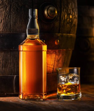 Viski şişesi ve bir bardak viski. Arka planda eski ahşap fıçı.