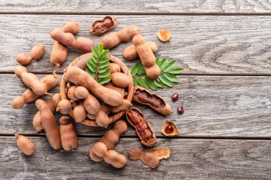 Olgun demirhindi meyvesi, yapraklar ve ahşap masada biraz demirhindi tohumu..