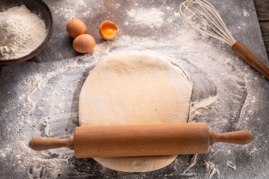 Pişmiş hamura hazır. Tahta, merdane, un ve hamurun üst görünümü.