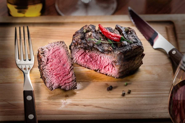 Grilled medium rare steak Mignon on wooden board ready to be eaten.