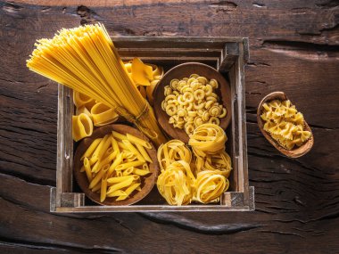 Different types of pasta in the wooden crate. Top view.