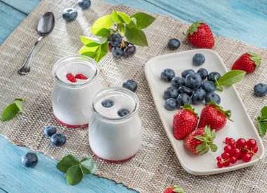 Sade yoğurt ve masada böğürtlen bulunan iki cam kap. Hafif yaz havası.