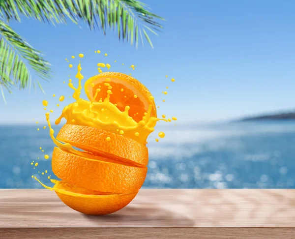 Juicy sliced orange with orange splash. Blue sparkling sea at the background.