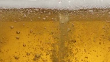 Bir bardak biranın içindekileri yakından çek. Bira kadehte, dalgalarda, köpüklerde ve köpüklerde yavaşça sallanır..