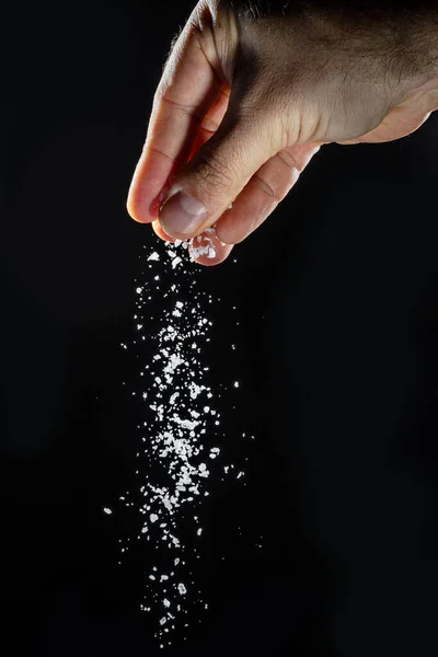 Mężczyzna Ręka Posypywanie Jadalną Sól Czarnym Tle — Zdjęcie stockowe