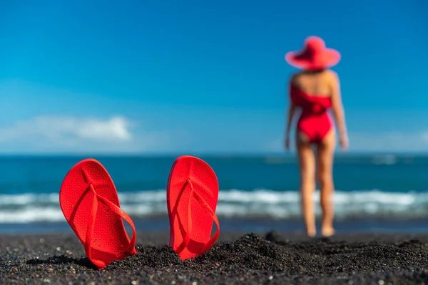 Röda Flip Flops Svart Sand Och Silhuett Kvinna Röd Baddräkt — Stockfoto