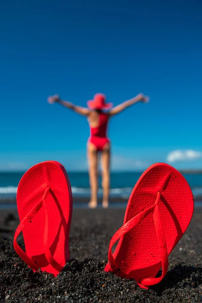Rote Flip Flops Schwarzen Sand Und Die Silhouette Einer Frau — Stockfoto