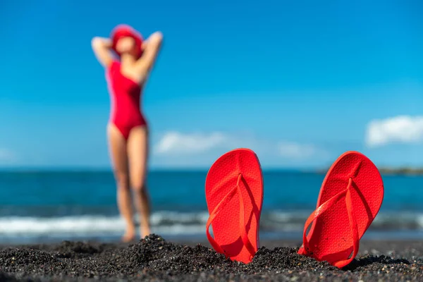 红色的翻滚在黑色的沙滩上 红色泳衣的女人站在海滩上 夏季概念 — 图库照片