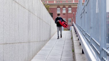 Eve teslimat yapmak için kırmızı çantalı bir teslimatçı.