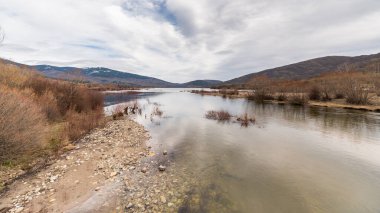 Dağlar, Lozoya del Valle, Madrid, İspanya 'da bulutlu bir günde rezervuara yansıdı.