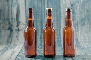 Farklı renkte bira şişeleri mavi arka planda farklı renkte kapaklar.