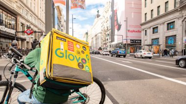 Madrid, Spain - Enero 8 2022: Mensajero con mochila amarilla y bicicleta por las calles de Madrid