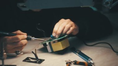 Adam lehimli bir elektronik güç ünitesini tamir ediyor.