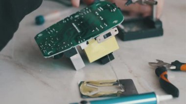 Adam lehimli bir elektronik güç ünitesini tamir ediyor.