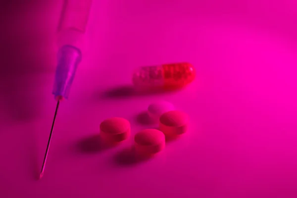 霓虹灯下的注射器 药丸和胶囊 — 图库照片