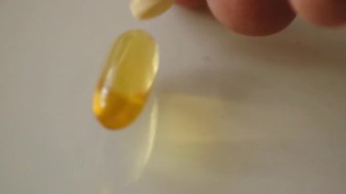 Düşen haplar ve kapsüller yavaş çekimde ışık yüzeyine düşüyor.