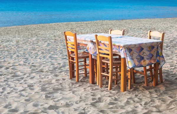 Ελληνική Ταβέρνα τραπέζι και καρέκλες σε αμμώδη παραλία — Φωτογραφία Αρχείου