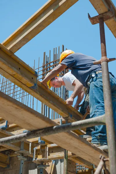 Trabalhadores da construção que colocam vigas de cofragem — Fotografia de Stock