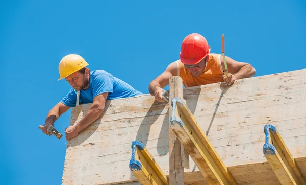 Travailleurs de la construction clouant coffrage de ciment en place Photo De Stock