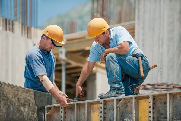 Dos trabajadores de la construcción instalando marcos de encofrado de hormigón — Foto de Stock