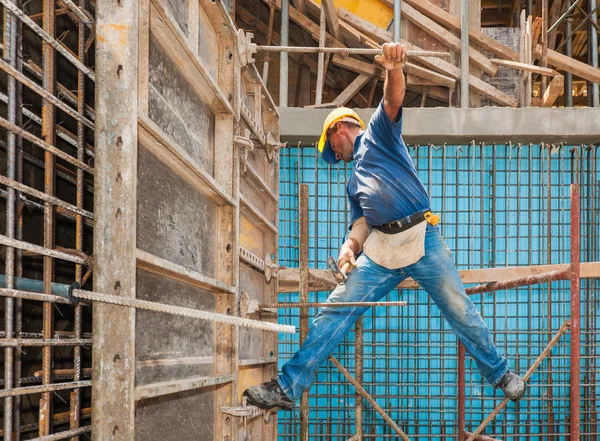 Obrero de la construcción equilibrio entre andamio y encofrado fram Fotos de stock