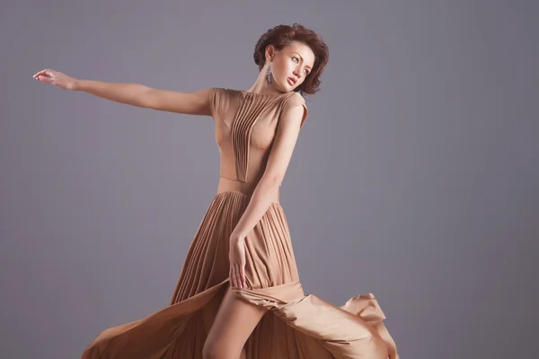 Sexy woman in fluttering gold dress — Stock Photo, Image