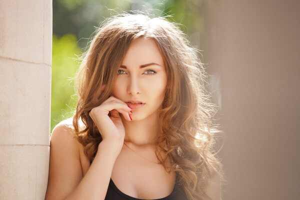 Beautiful young woman standing near old columns