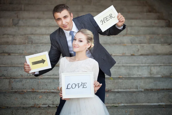 Happy Groom and Bride in a park with signs — Stock Photo, Image