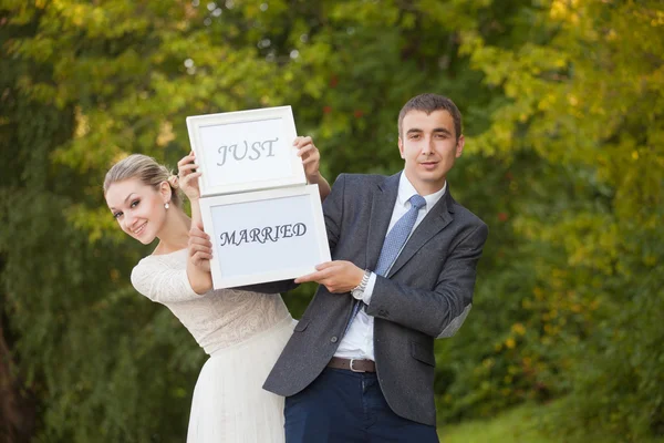 Happy Groom and Bride in a park with signs — Stock Photo, Image