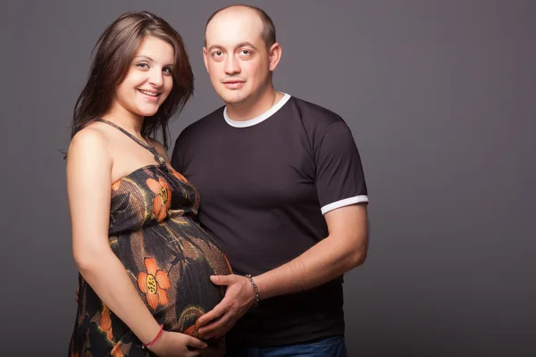Gravidez jovem mulher com homem em estúdio — Fotografia de Stock