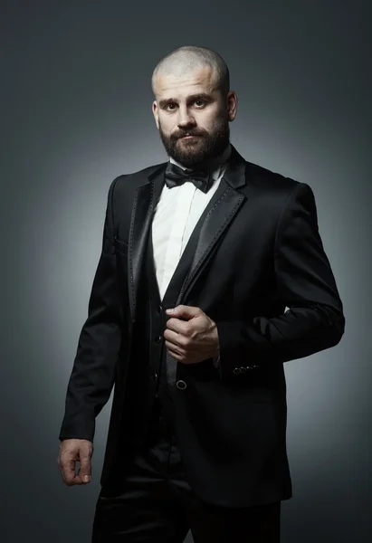 Стильный и грубый лысый мужчина с бородой в элегантном черном костюме — стоковое фото