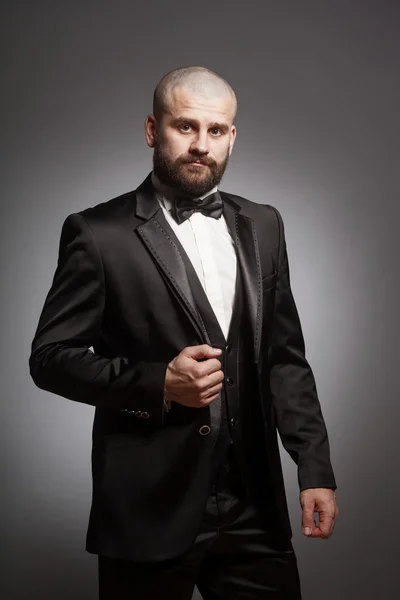 Stylish and brutal bald man with a beard in elegant black suit — Stock Photo, Image