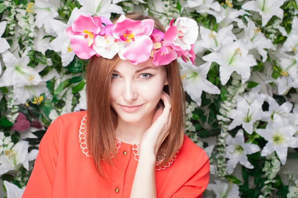 Mujer joven hermosa y de moda cerca de la pared de flores — Foto de Stock