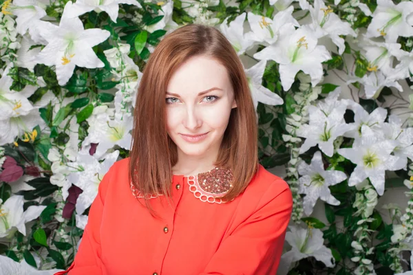 Beautiful and fashion young woman near the wall of flowers — Stock Photo, Image