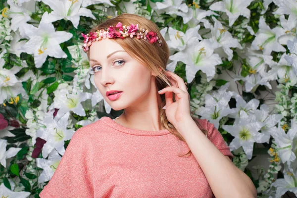 Schöne und modische junge Frau nahe der Blumenmauer — Stockfoto