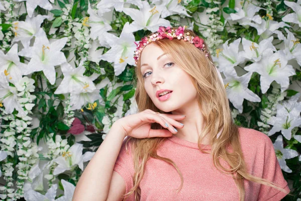 Mujer joven hermosa y de moda cerca de la pared de flores — Foto de Stock
