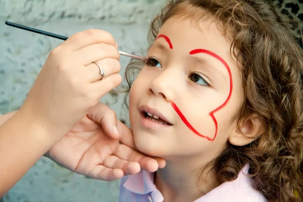 Klein meisje krijgen haar gezicht geschilderd — Stockfoto