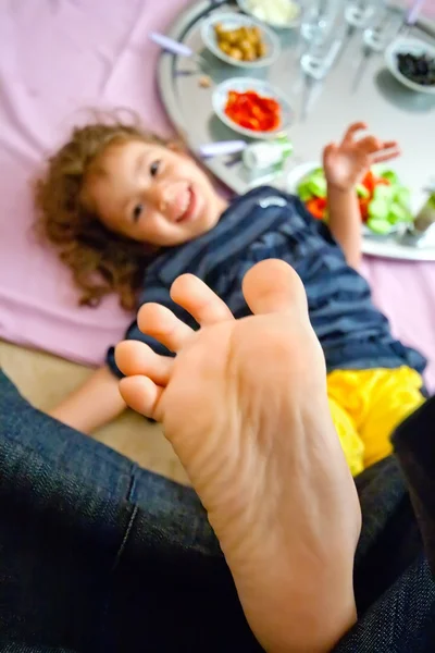 Holčička hraje dotýkání nohou pod stolem — Stock fotografie